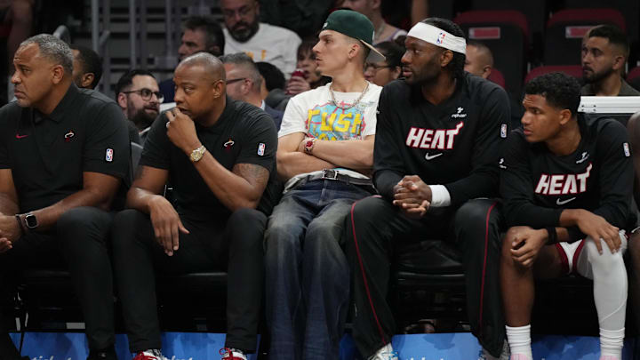 Oct 17, 2025; Miami, Florida, USA;  Miami Heat guard Tyler Herro, center, looks on from the bench as he continues to heal from foot surgery at Kaseya Center. Mandatory Credit: Jim Rassol-Imagn Images