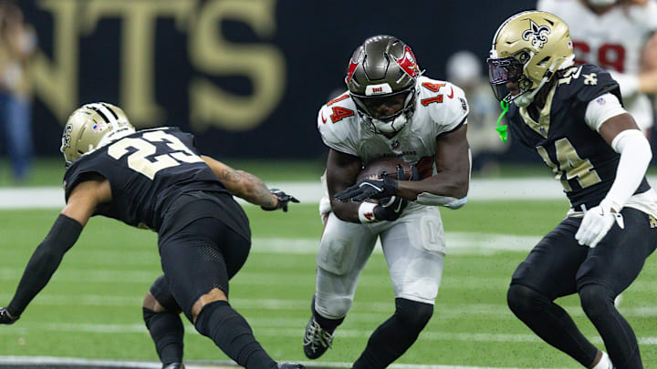 Oct 13, 2024; New Orleans, Louisiana, USA;  Tampa Bay Buccaneers wide receiver Chris Godwin (14) slips between New Orleans Saints cornerback Marshon Lattimore (23) and New Orleans Saints cornerback Kool-Aid McKinstry (14) during the first half at Caesars Superdome. Mandatory Credit: Stephen Lew-Imagn Images