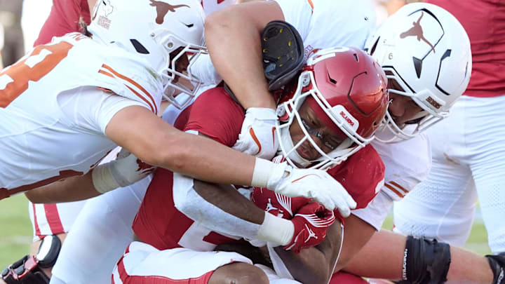 Oklahoma Sooners running back Jovantae Barnes (2) is brought down by Texas Longhorns linebacker Colin Simmons, bottom, linebacker Liona Lefau (18), left, and defensive lineman Jermayne Lole (99) during the Red River Rivalry college football game between the University of Oklahoma Sooners (OU) and the Texas Longhorns at the Cotton Bowl in Dallas, Saturday, Oct. 12, 2024. Texas one 34-3.