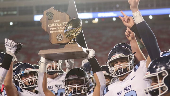 Bay Port's Nick Hawker hoists the championship trophy as he celebrates with teammates after defeating Muskego in the WIAA Division 1 state championship game Friday, Nov. 22, 2024, at Camp Randall Stadium in Madison, Wis. Bay Port won the game, 25-18.