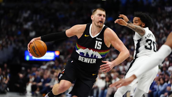 Apr 4, 2026; Denver, Colorado, USA; Denver Nuggets center Nikola Jokic (15) drives past San Antonio Spurs forward Julian Champagnie (30) in the first quarter at Ball Arena. Mandatory Credit: Ron Chenoy-Imagn Images