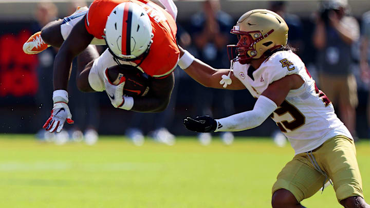 Oct 5, 2024; Charlottesville, Virginia, USA; Virginia Cavaliers running back Kobe Pace (5) dives into Boston College Eagles defensive back Cameron Martinez (29) during the third quarter at Scott Stadium. Mandatory Credit: Peter Casey-Imagn Images