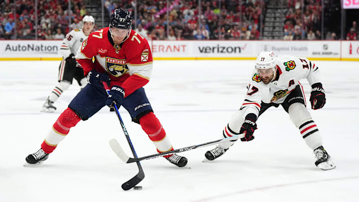 Nov 12, 2023; Sunrise, Florida, USA; Chicago Blackhawks left wing Nick Foligno (17) reaches for the puck on Florida Panthers defenseman Niko Mikkola (77) during the first period at Amerant Bank Arena. Mandatory Credit: Jasen Vinlove-Imagn Images