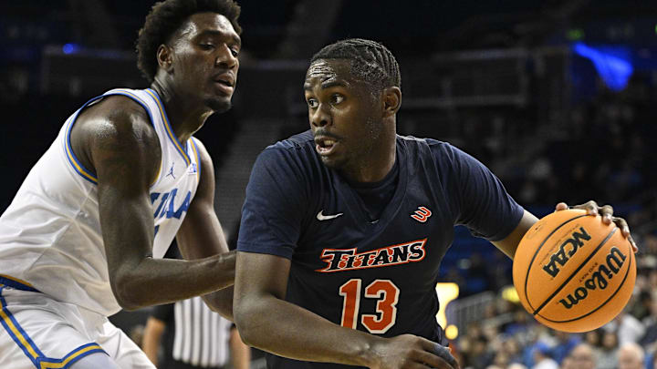Nov 22, 2024; Los Angeles, California, USA; Cal State Fullerton Titans guard Kaleb Brown (13) drives to the basket past UCLA Bruins guard Eric Dailey Jr. (3) during the first half at Pauley Pavilion presented by Wescom. Mandatory Credit: Robert Hanashiro-Imagn Images