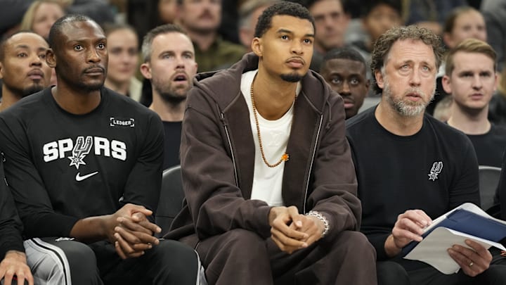 Dec 2, 2025; San Antonio, Texas, USA; San Antonio Spurs forward Victor Wembanyama (1) along with center Bismack Biyombo (18) and assistant coach Matt Nielsen