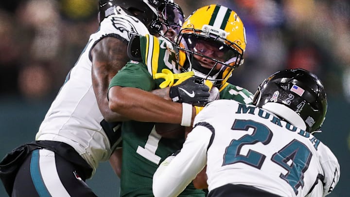 Green Bay Packers wide receiver Dontayvion Wicks (13) is tackled by Philadelphia Eagles cornerback Quinyon Mitchell and safety Andrew Mukuba (24) on Monday, November 10, 2025, at Lambeau Field in Green Bay, Wis. The Eagles won the game, 10-7.