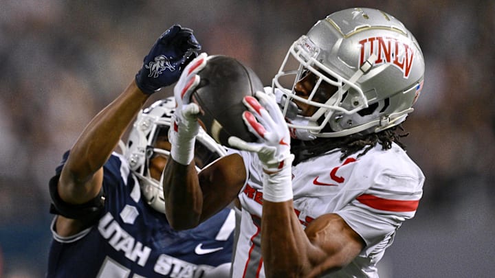 UNLV Rebels wide receiver Ricky White III (11) catches a touchdown pass in front of Utah State Aggies cornerback Avante Dickerson (17) in the first half at Merlin Olsen Field at Maverik Stadium. 