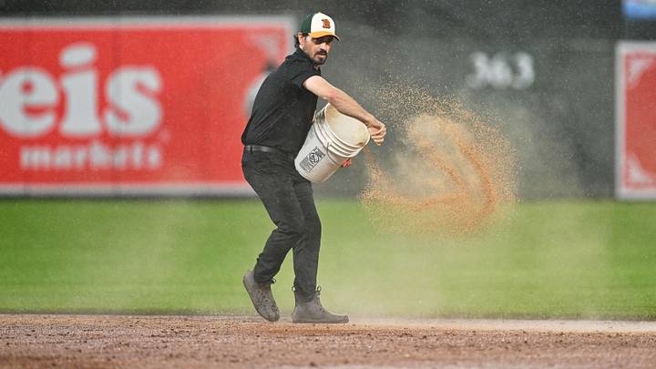A member of the grounds crew spreads dirt on the infield before the ninth inning as rain continues to fall during the game between the Baltimore Orioles and the Detroit Tigers.