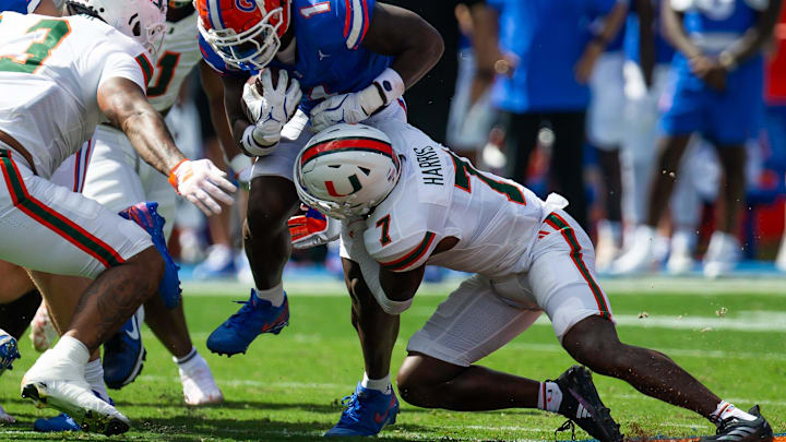 Florida Gators running back Montrell Johnson Jr. (1) finds a hole as Miami Hurricanes defensive back Jaden Harris (7) tackles him during the season opener at Ben Hill Griffin Stadium in Gainesville, FL on Saturday, August 31, 2024 against the University of Miami Hurricanes in the first half. [Doug Engle/Gainesville Sun]