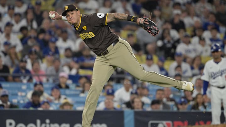Oct 6, 2024; Los Angeles, California, USA; San Diego Padres third baseman Manny Machado (13) attempts to throw to first against Los Angeles Dodgers outfielder Tommy Edman (25) in the eighth inning during game two of the NLDS for the 2024 MLB Playoffs at Dodger Stadium. Mandatory Credit: Jayne Kamin-Oncea-Imagn Images