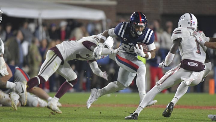 Nov 29, 2024; Oxford, Mississippi, USA; Mississippi Rebels running back Domonique Thomas (26) runs the ball while defended by Mississippi State Bulldogs running back Davon Booth (21) during the fourth quarter at Vaught-Hemingway Stadium. Mandatory Credit: Matt Bush-Imagn Images