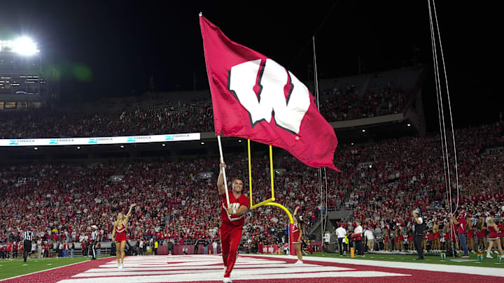 Aug 28, 2025; Madison, Wisconsin, USA; A Wisconsin Badgers cheerleader carries a Wisconsin flag during the game against the Miami (OH) RedHawks at Camp Randall Stadium. Aug 28, 2025; Madison, Wisconsin, USA; A Wisconsin Badgers cheerleader carries a Wisconsin flag during the game against the Miami (OH) RedHawks at Camp Randall Stadium.