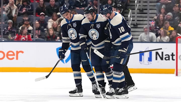 Blue Jackets Mason Marchment and Dmitri Voronkov help an injured Miles Wood off the ice.