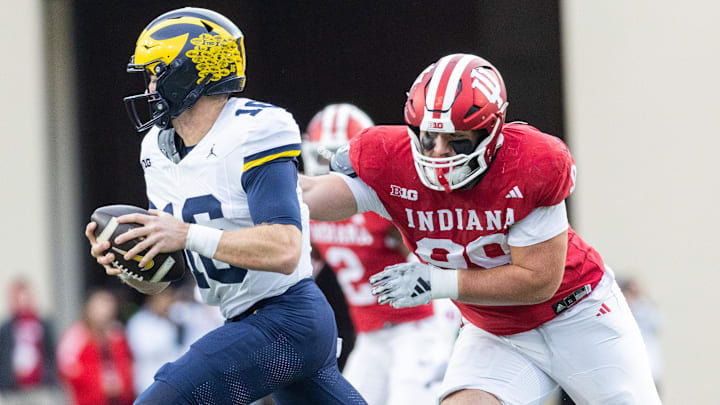 Michigan Wolverines quarterback Davis Warren (16) runs with the ball while Indiana Hoosiers defensive lineman James Carpenter (99) defends in the second quarter at Memorial Stadium.