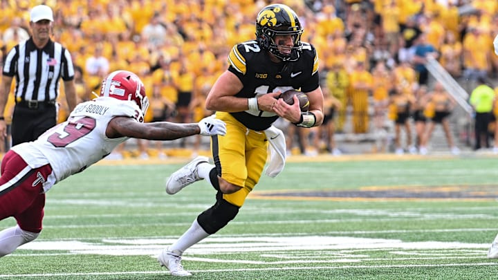 Sep 14, 2024; Iowa City, Iowa, USA; Iowa Hawkeyes quarterback Cade McNamara (12) attempts to elude Troy Trojans safety Ian Conerly-Goodly (39) during the first quarter at Kinnick Stadium. Mandatory Credit: Jeffrey Becker-Imagn Images
