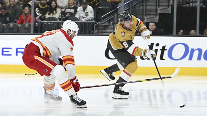 Dec 29, 2024; Las Vegas, Nevada, USA;  Vegas Golden Knights center Jack Eichel (9) shoots the puck past Calgary Flames defenseman Kevin Bahl (7) in the second period of their game at T-Mobile Arena. Mandatory Credit: Candice Ward-Imagn Images