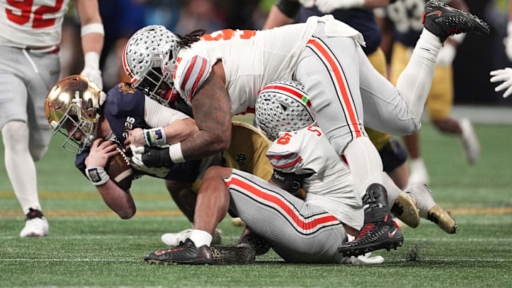 Jan 20, 2025; Atlanta, GA, USA; Notre Dame Fighting Irish quarterback Riley Leonard (13) is tackled by Ohio State Buckeyes safety Sonny Styles (6) and Ohio State Buckeyes defensive tackle Tyleik Williams (91) in the second half in the CFP National Championship
