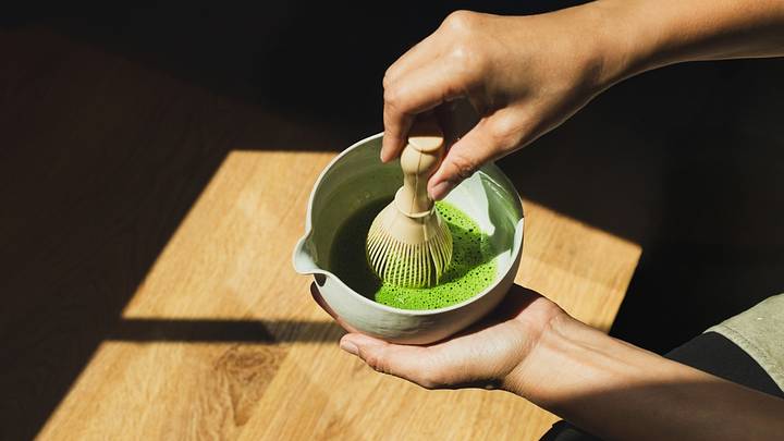 Person preparing matcha with bamboo whisk