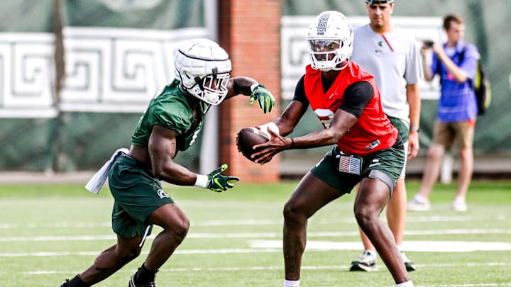 Michigan State's Nathan Carter, left, takes a handoff from quarterback Aidan Chiles during the first day of football camp on Tuesday, July 30, 2024, in East Lansing.