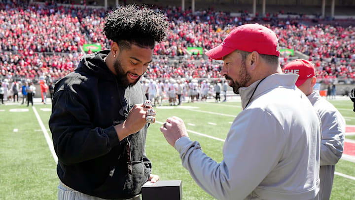 Ohio State Buckeyes head coach Ryan Day talks about the championship ring to former Buckeye JT Tuimoloau after he received a box of three rings for winning the College Football Playoffs during the spring game at Ohio Stadium on April 12, 2025. Players and coaches from the 2024 championship team received a ring for making the College Football Playoff, one from the CFP for winning it and a championship ring from Ohio State.