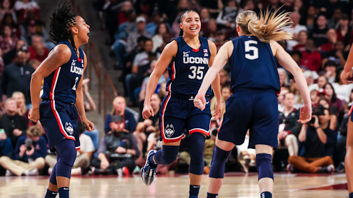 UConn Huskies guards KK Arnold, Azzi Fudd, and Paige Bueckers celebrate a three-point basket against the South Carolina Gamecocks.