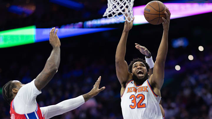 Nov 12, 2024; Philadelphia, Pennsylvania, USA; New York Knicks center Karl-Anthony Towns (32) drives for a shot next to Philadelphia 76ers center Andre Drummond (5) during the second quarter at Wells Fargo Center. Mandatory Credit: Bill Streicher-Imagn Images