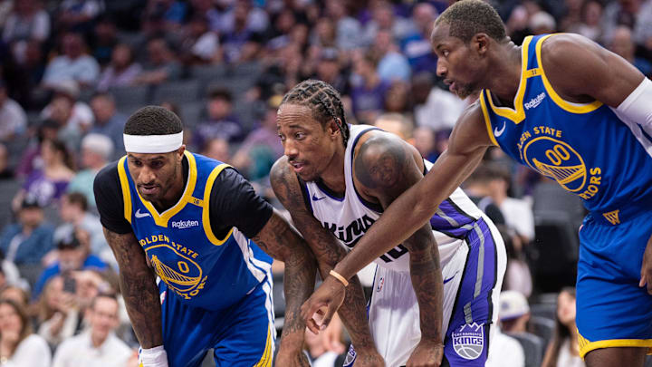 Oct 9, 2024; Sacramento, California, USA; Golden State Warriors guard Gary Payton II (0) and forward Jonathan Kuminga (00) defend against Sacramento Kings forward DeMar DeRozan (10) during a free throw attempt in the second quarter at Golden 1 Center. Mandatory Credit: Ed Szczepanski-Imagn Images