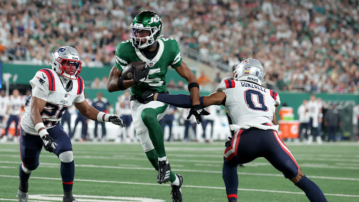 Sep 19, 2024; East Rutherford, New Jersey, USA; New York Jets wide receiver Garrett Wilson (5) runs with the ball against New England Patriots cornerbacks Marcus Jones (25) and Christian Gonzalez (0) during the third quarter at MetLife Stadium. Mandatory Credit: Brad Penner-Imagn Images