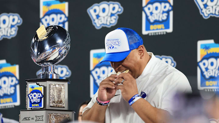 Dec 27, 2025; Orlando, FL, USA; BYU Cougars head coach Kalani Sitake  eats a pop-tart and celebrates after they beat the against the Georgia Tech Yellow Jackets at Camping World Stadium. Mandatory Credit: Kim Klement Neitzel-Imagn Images