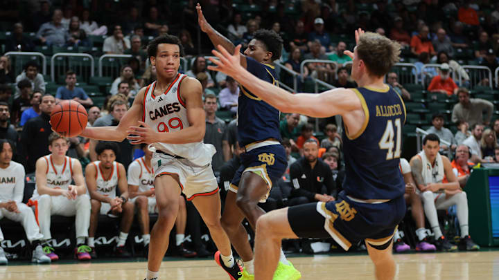 Feb 1, 2025; Coral Gables, Florida, USA; Miami Hurricanes guard Divine Ugochukwu (99) passes the basketball as Notre Dame Fighting Irish guard Markus Burton (3) and guard Matt Allocco (41) defend during the second half at Watsco Center. Mandatory Credit: Sam Navarro-Imagn Images Feb 1, 2025; Coral Gables, Florida, USA; Miami Hurricanes guard Divine Ugochukwu (99) passes the basketball as Notre Dame Fighting Irish guard Markus Burton (3) and guard Matt Allocco (41) defend during the second half at Watsco Center. Mandatory Credit: Sam Navarro-Imagn Images