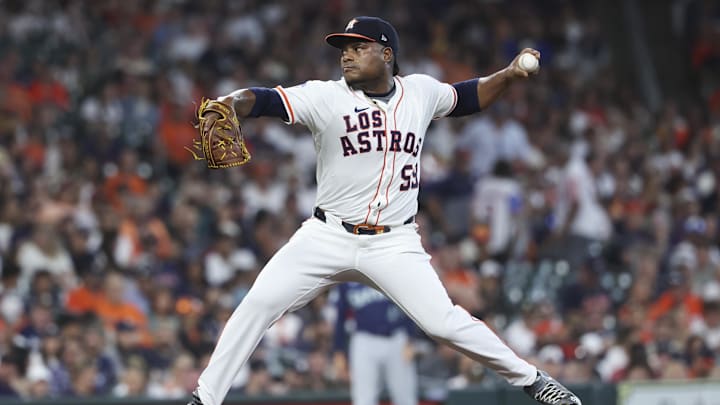 Houston Astros pitcher Framber Valdez throws a baseball with his left hand in a white uniform and a dark hat. Houston Astros pitcher Framber Valdez throws a baseball with his left hand in a white uniform and a dark hat.