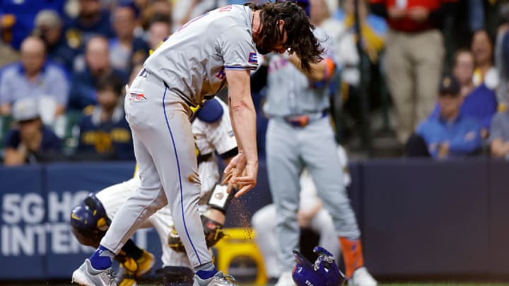 Jesse Winker smashes his helmet after scoring a run in the ninth inning. 