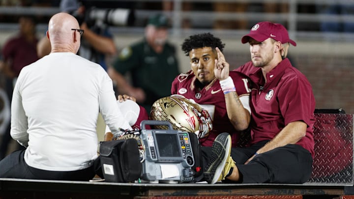 Nov 18, 2023; Tallahassee, Florida, USA; Florida State Seminoles quarterback Jordan Travis (13) waves to fans while being carted off after an injury against the North Alabama Lions during the first quarter at Doak S. Campbell Stadium. Mandatory Credit: Morgan Tencza-Imagn Images