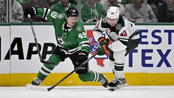 Apr 9, 2026; Dallas, Texas, USA; Dallas Stars center Justin Hryckowian (49) and Minnesota Wild defenseman Quinn Hughes (43) battle for the puck during the game between the Stars and the Wild at American Airlines Center. Mandatory Credit: Jerome Miron-Imagn Images