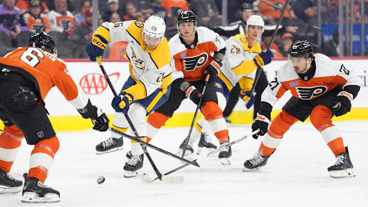 Mar 31, 2025; Philadelphia, Pennsylvania, USA; Nashville Predators left wing Kieffer Bellows (26) reaches for the puck against Philadelphia Flyers left wing Noah Cates (27) in the first period at Wells Fargo Center. 