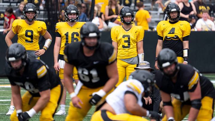 Iowa quarterbacks Hank Brown (9), Ryan Fitzgerald (16), Jimmy Sullivan (3) and Tradon Bessinger (4) watch a drill Aug. 15, 2026 during the Kids Day at Kinnick open practice at Kinnick Stadium in Iowa City, Iowa.