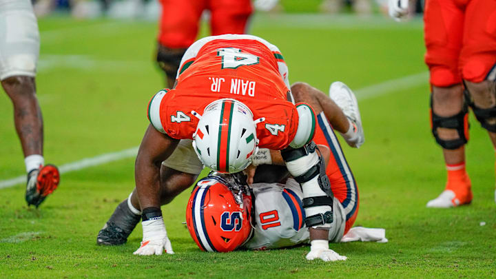 Nov 8, 2025; Miami Gardens, Florida, USA; Syracuse Orange quarterback Rickie Collins (10) is sacked by Miami Hurricanes defensive lineman Rueben Bain Jr. (4) during the fourth quarter at Hard Rock Stadium. Mandatory Credit: Jeff Romance-Imagn Images Nov 8, 2025; Miami Gardens, Florida, USA; Syracuse Orange quarterback Rickie Collins (10) is sacked by Miami Hurricanes defensive lineman Rueben Bain Jr. (4) during the fourth quarter at Hard Rock Stadium. Mandatory Credit: Jeff Romance-Imagn Images
