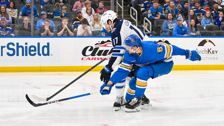 Apr 9, 2026; St. Louis, Missouri, USA; Winnipeg Jets center Adam Lowry (17) controls the puck as St. Louis Blues defenseman Philip Broberg (6) defends during the third period at Enterprise Center. Mandatory Credit: Jeff Curry-Imagn Images