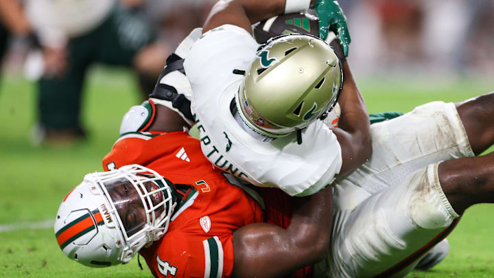 Sep 13, 2025; Miami Gardens, Florida, USA; Miami Hurricanes defensive lineman Rueben Bain Jr. (4) tackles South Florida Bulls wide receiver Christian Neptune (81) in the third quarter at Hard Rock Stadium. Mandatory Credit: Nathan Ray Seebeck-Imagn Images