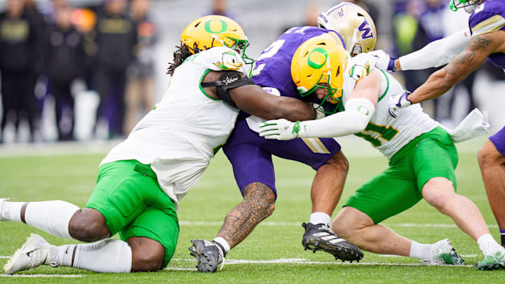 Oregon defensive lineman Bear Alexander, left, and Oregon defensive back Dillon Thieneman bring down Washington quarterback Demond Williams Jr. as the Oregon Ducks take on the Washington Huskies on Nov. 29, 2025, at Husky Stadium in Seattle, Washington. Oregon defensive lineman Bear Alexander, left, and Oregon defensive back Dillon Thieneman bring down Washington quarterback Demond Williams Jr. as the Oregon Ducks take on the Washington Huskies on Nov. 29, 2025, at Husky Stadium in Seattle, Washington.