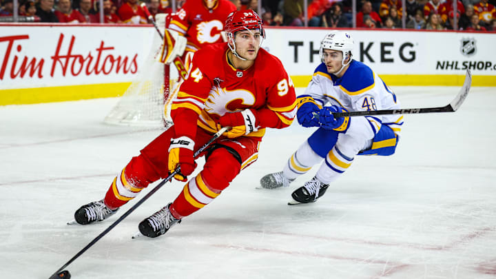 Jan 23, 2025; Calgary, Alberta, CAN; Calgary Flames defenseman Brayden Pachal (94) controls the puck against Buffalo Sabres center Tyson Kozak (48) during the third period at Scotiabank Saddledome. Mandatory Credit: Sergei Belski-Imagn Images