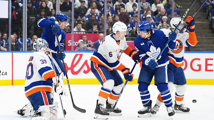 Dec 31, 2024; Toronto, Ontario, CAN; Toronto Maple Leafs left wing Nicholas Robertson (89) battles for the puck in front of the net with New York Islanders defenseman Ryan Pulock (6) during the third period at the Scotiabank Arena. Mandatory Credit: Nick Turchiaro-Imagn Images