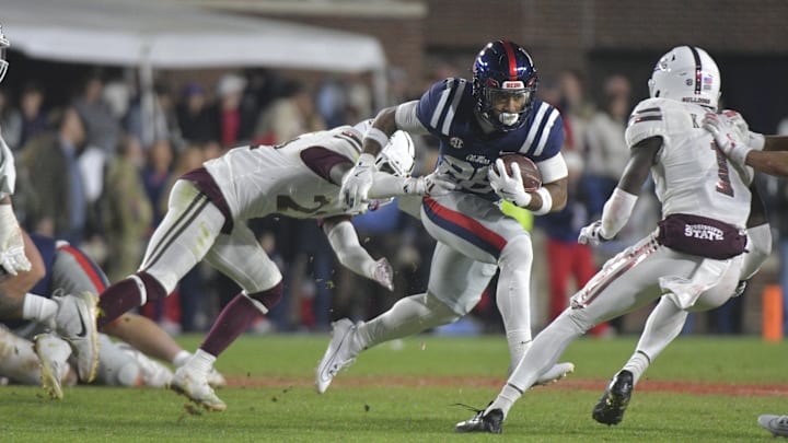 Nov 29, 2024; Oxford, Mississippi, USA; Mississippi Rebels running back Domonique Thomas (26) runs the ball while defended by Mississippi State Bulldogs running back Davon Booth (21) during the fourth quarter at Vaught-Hemingway Stadium. Mandatory Credit: Matt Bush-Imagn Images