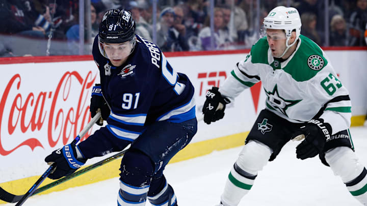 Mar 14, 2025; Winnipeg, Manitoba, CAN;  Winnipeg Jets forward Cole Perfetti (91) and Dallas Stars forward Wyatt Johnston (53) skate for the puck during the second period at Canada Life Centre. Mandatory Credit: Terrence Lee-Imagn Images