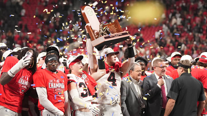 Dec 6, 2025; Atlanta, GA, USA; ç (4) and Georgia Bulldogs running back Cash Jones (32) lift the SEC Championship trophy after the game against the Alabama Crimson Tide during the 2025 SEC Championship game at Mercedes-Benz Stadium. Mandatory Credit: Dale Zanine-Imagn Images