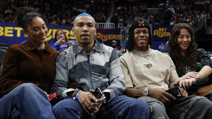 Detroit Lions wide receiver St. Brown and running back Gibbs sit court side during the game between the Detroit Pistons and the Golden State Warriors at Little Caesars Arena. 