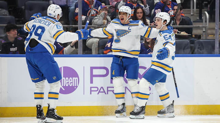 Nov 22, 2025; Elmont, New York, USA;  St. Louis Blues center Brayden Schenn (10) celebrates with left wing Pavel Buchnevich (89) and right wing Dalibor Dvorsky (54) after scoring a goal in the first period against the New York Islanders at UBS Arena. Mandatory Credit: Wendell Cruz-Imagn Images
