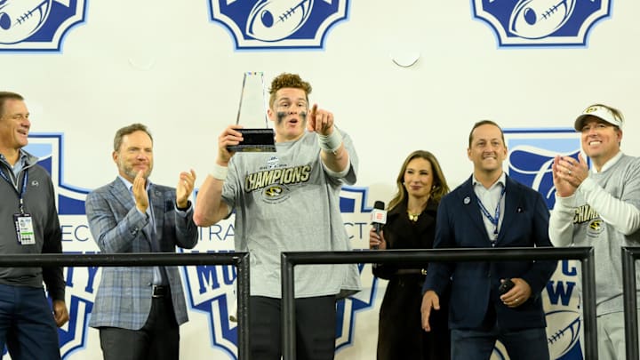 Dec 30, 2024; Nashville, TN, USA;  Missouri Tigers quarterback Brady Cook (12) holds his MVP trophy as he points to this team against the Iowa Hawkeyes during the trophy presentation at Nissan Stadium. Mandatory Credit: Steve Roberts-Imagn Images
