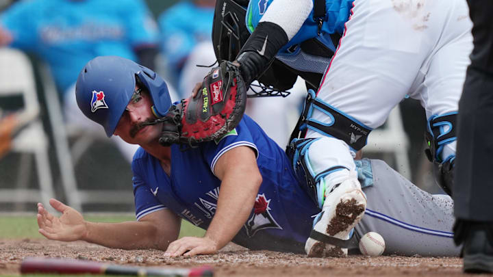 Mar 16, 2026; Jupiter, Florida, USA;  Toronto Blue Jays second baseman Davis Schneider (36) scores a run as Miami Marlins catcher Brian Navarreto (64) drops the ball at the plate in the third inning at Roger Dean Chevrolet Stadium. Mandatory Credit: Jim Rassol-Imagn Images