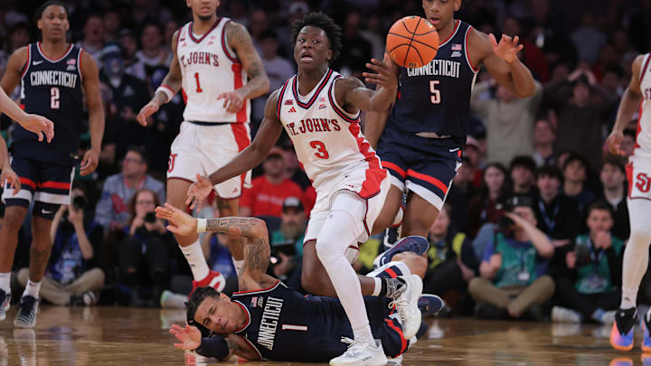 Mar 14, 2026; New York, NY, USA; Connecticut Huskies guard Solo Ball (1) falls to the court as St. John's Red Storm guard Joson Sanon (3) looks to handle the loose ball during the second half of the men's Big East Conference Tournament Championship at Madison Square Garden. Mandatory Credit: Brad Penner-Imagn Images